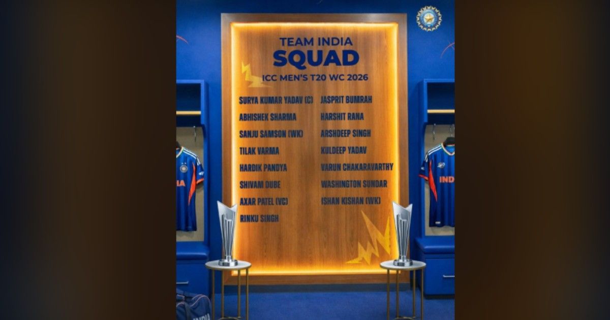 Team India ICC Men's T20 World Cup 2026 squad displayed on a wooden board in a locker room, with two trophies in front and blue jerseys hanging on either side.